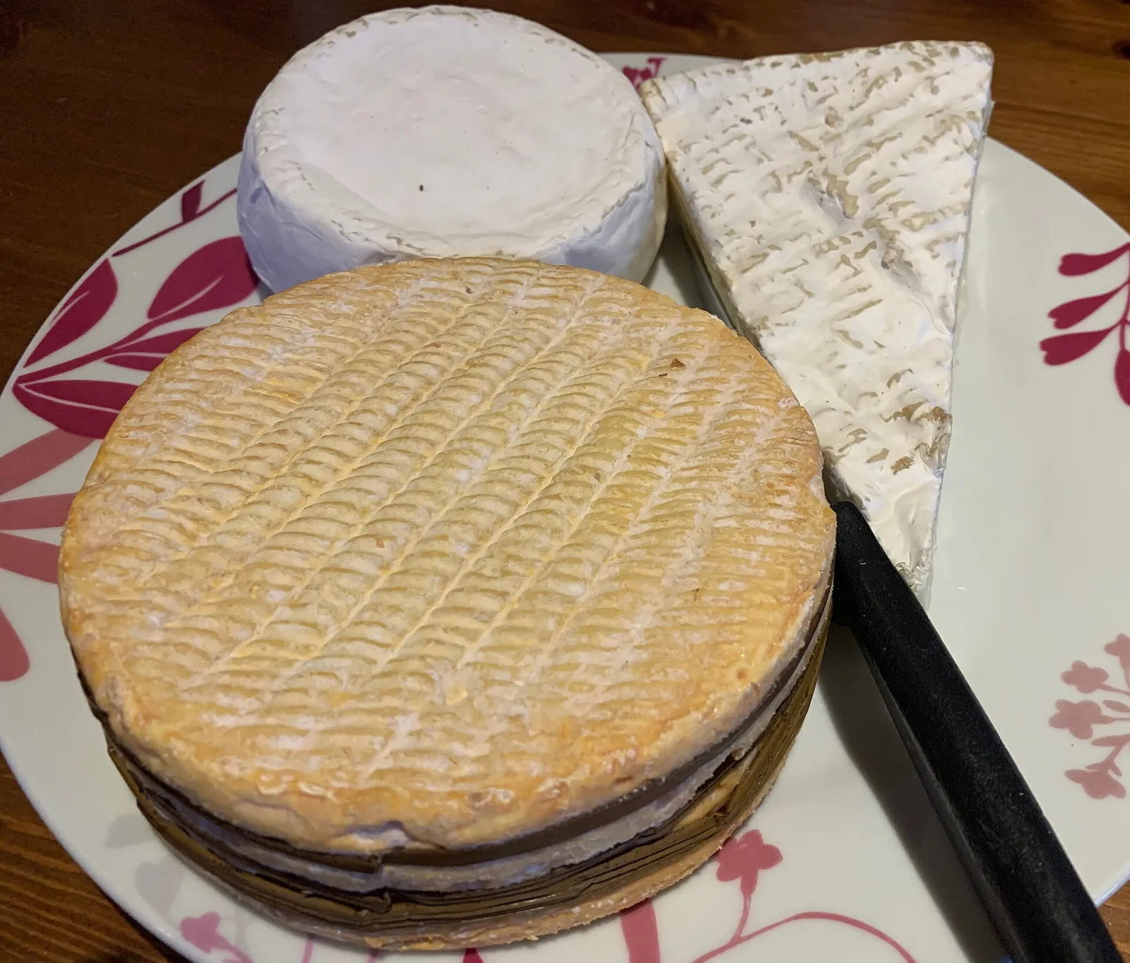 A plate with a slice of Brie de Meaux, a small round of buffalo-milk Camembert and a round of Livarot