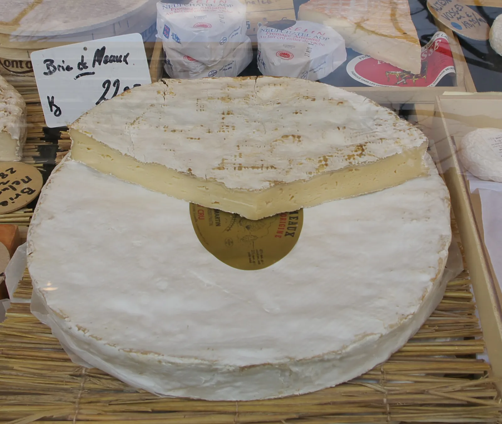 A large wheel of Brie de Meaux at a French market, one slice cut away