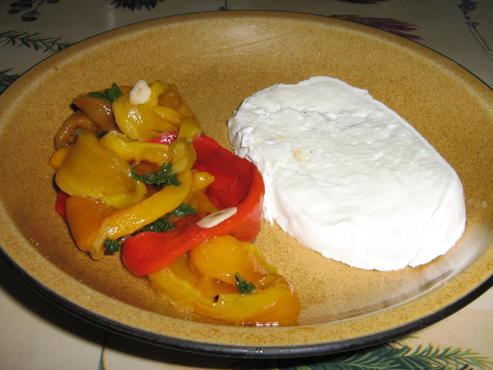 Buffalo mozzarella served with roasted red and yellow peppers on a plate