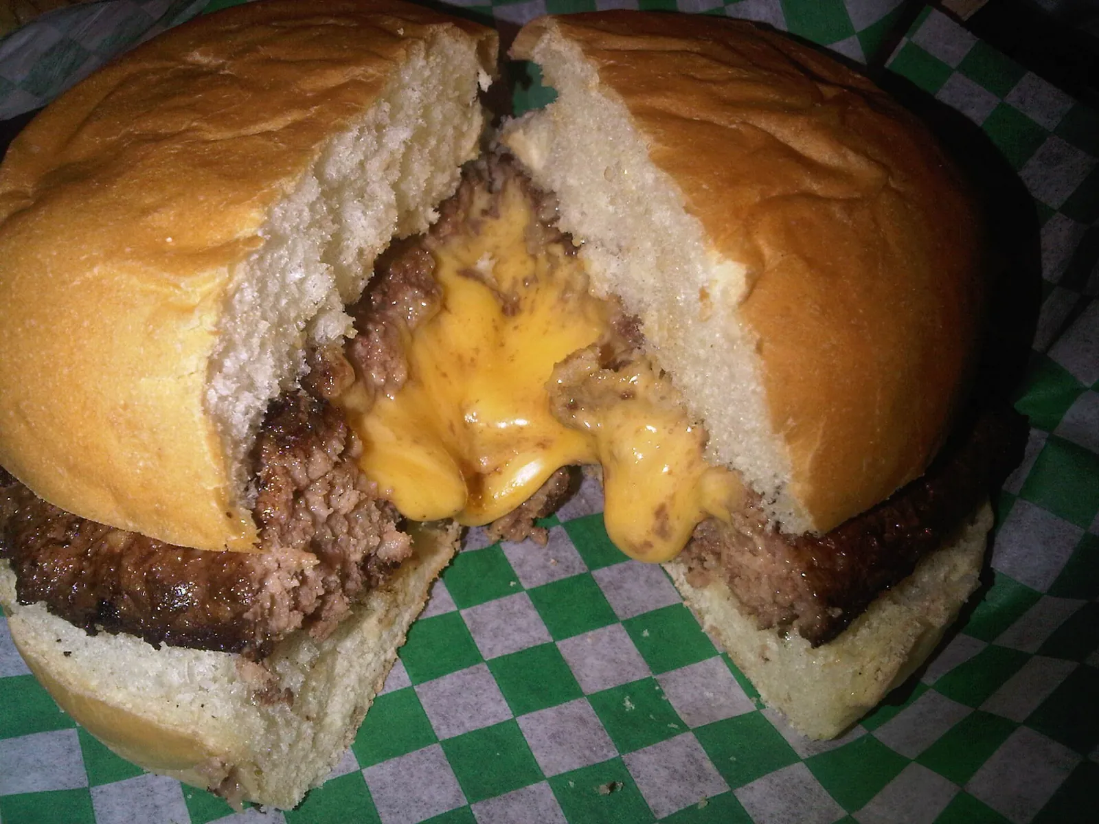 A cheese-stuffed burger cut in half with molten cheese running out