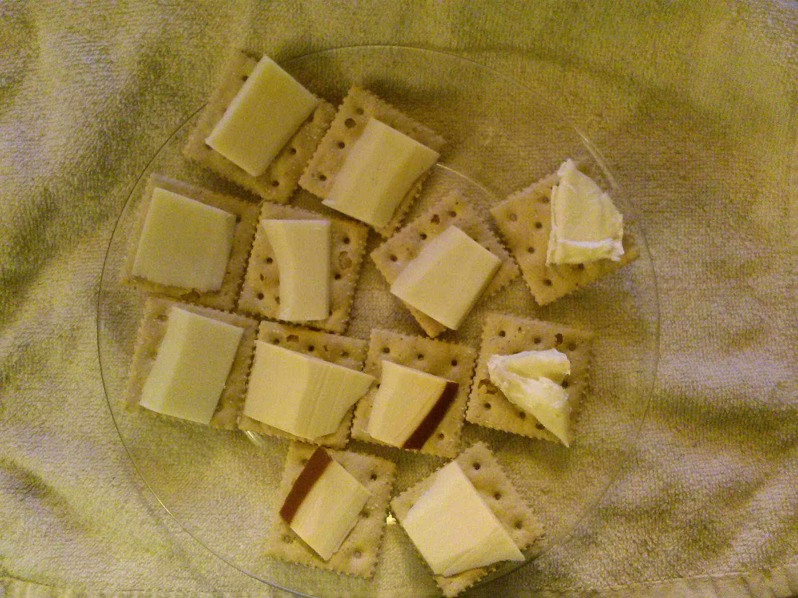 Squares of yellow cheese with crackers on a glass plate