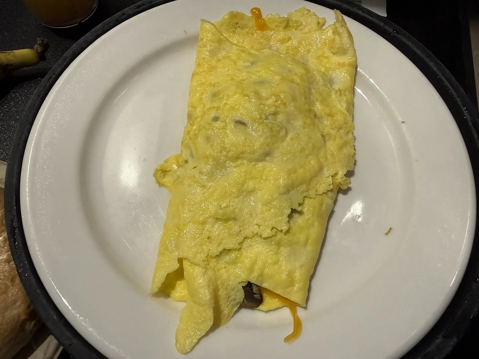 A folded yellow omelette filled with melted cheddar cheese, served on a white plate