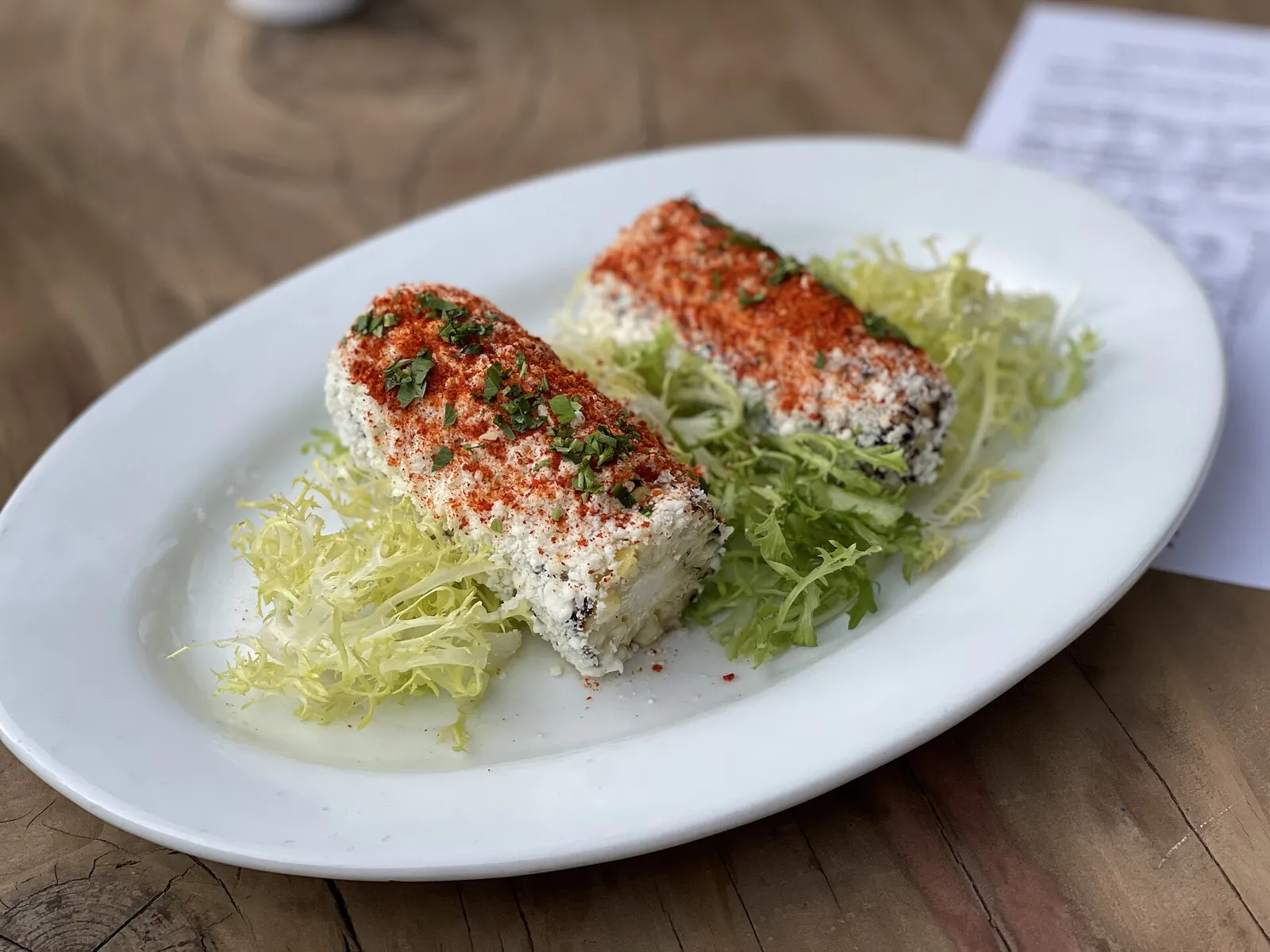 Grilled corn on a plate topped with crumbled cotija and chile