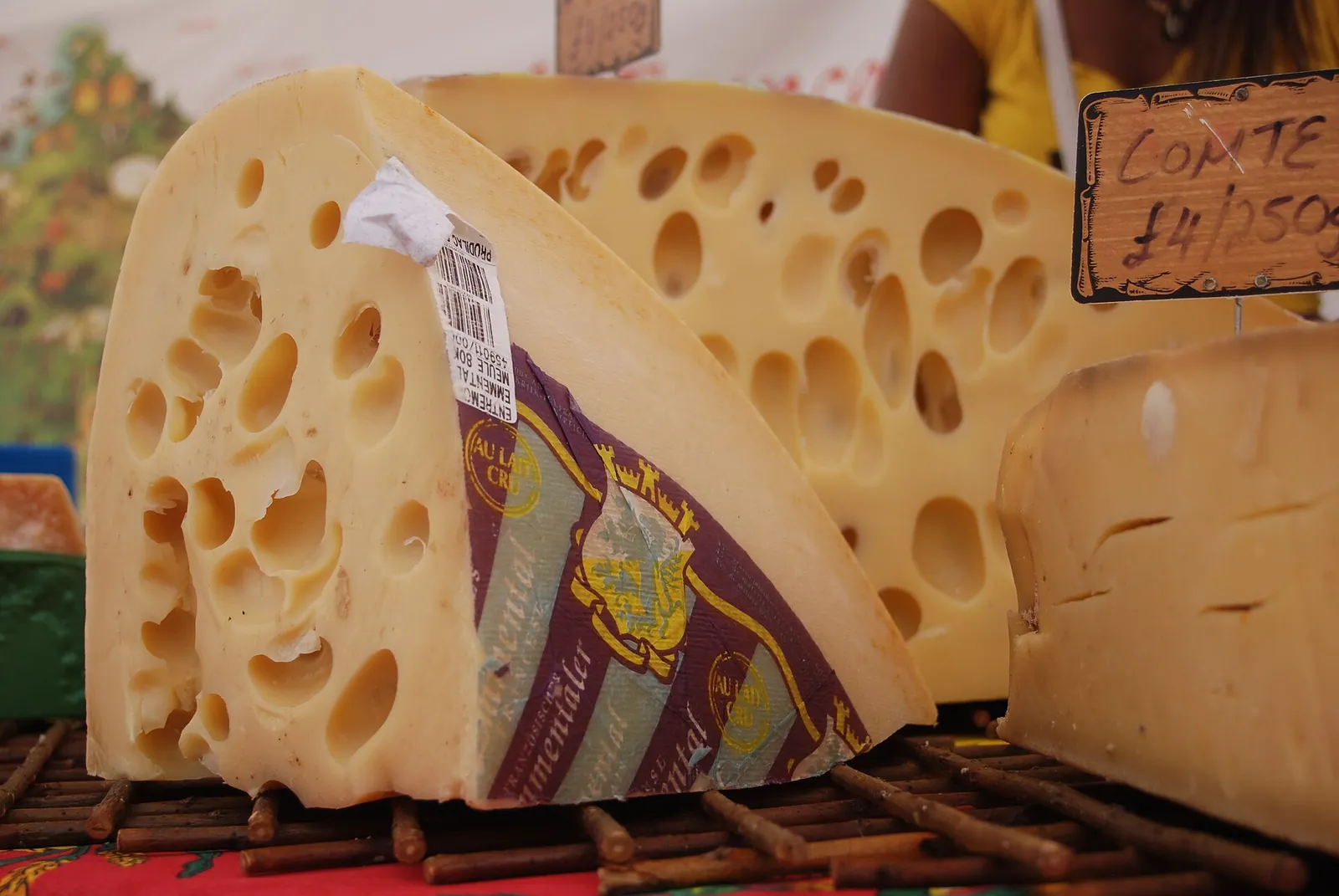 A large wedge of Emmental with big round holes on a market counter