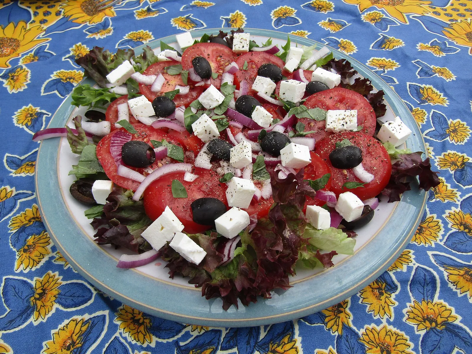 A Greek salad of tomato, red onion, black olives and cubes of feta on a platter
