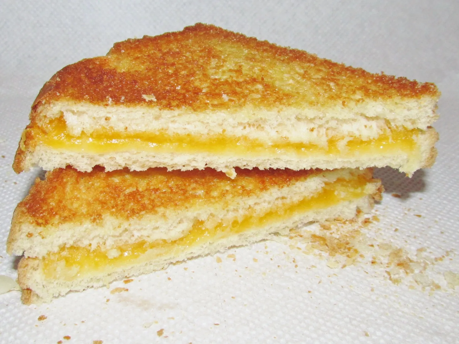 A grilled cheese sandwich cut in half, with melted yellow cheese between toasted bread