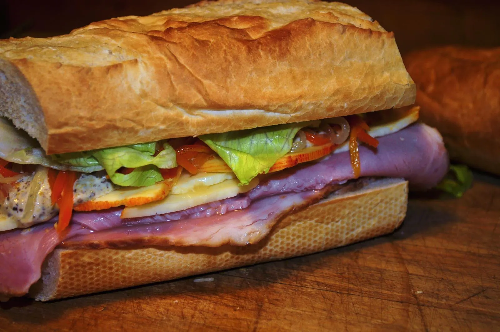 A ham and cheese sandwich on a baguette with layers of sliced cheese