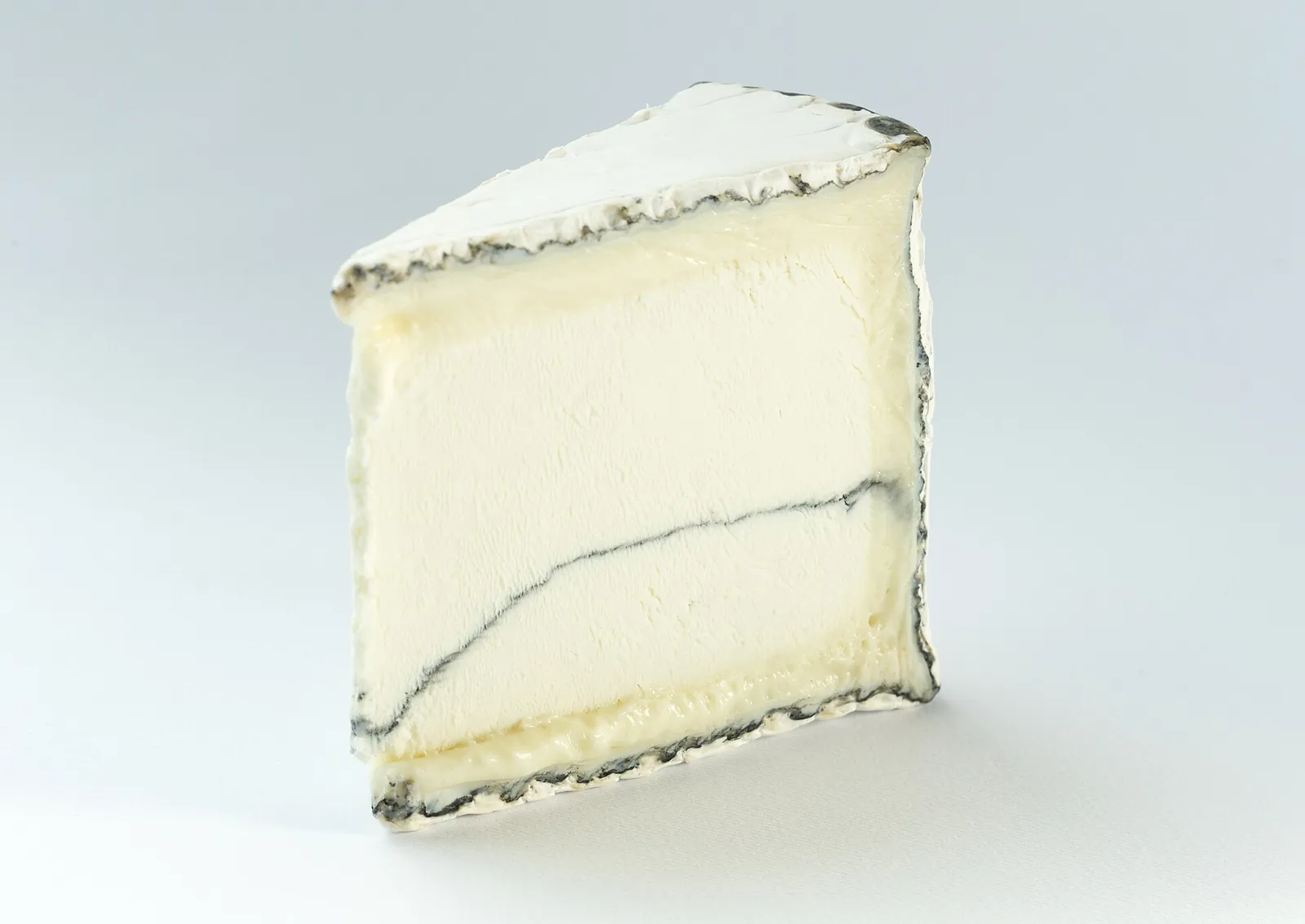 A wedge of Humboldt Fog showing its white paste, bloomy rind and thin line of ash