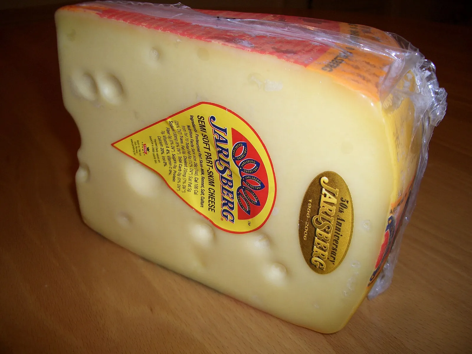 A wedge of Jarlsberg with round holes and its label on the rind