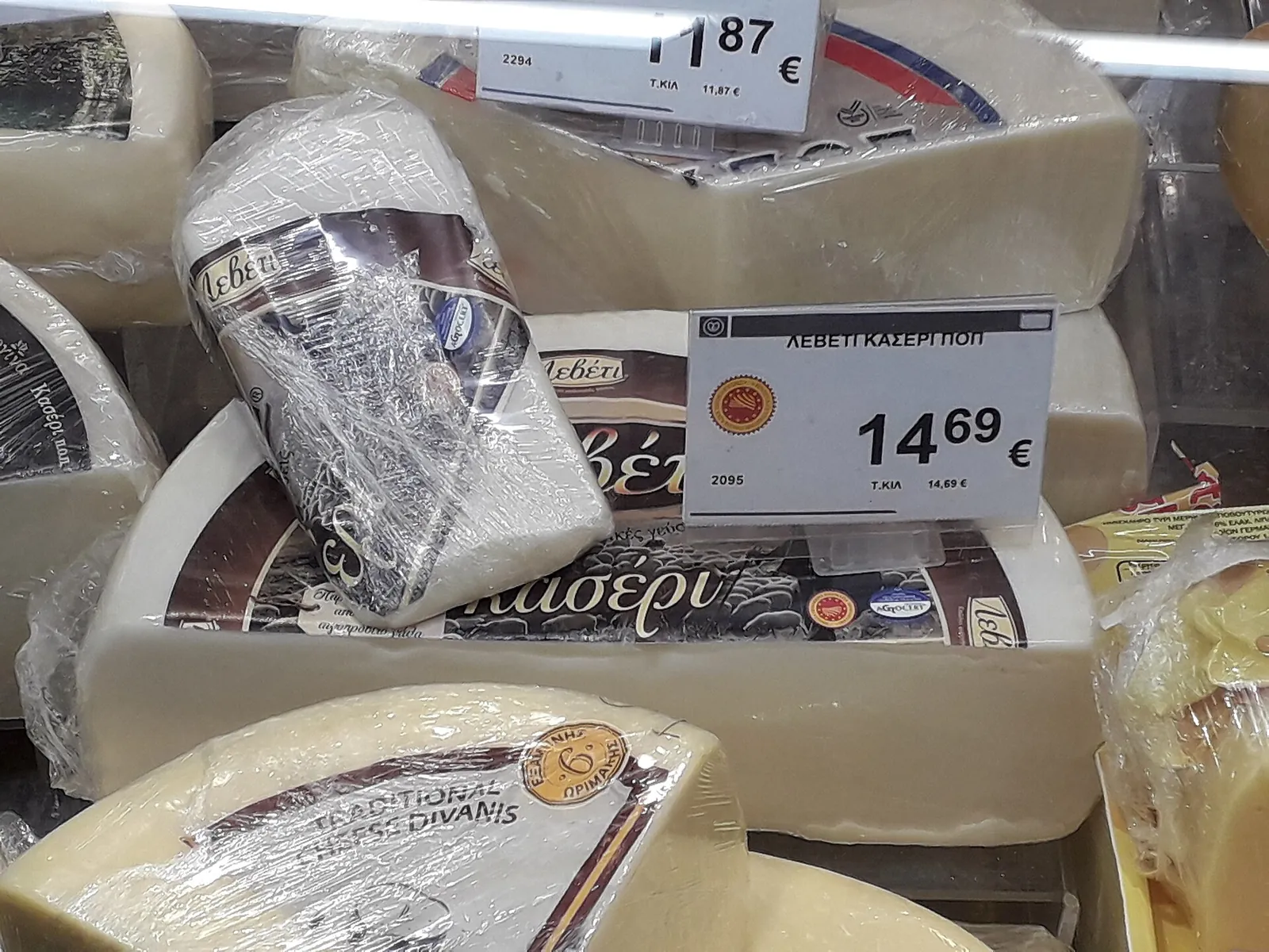 Wrapped wedges of Kasseri cheese with price labels stacked in a Greek supermarket cold case