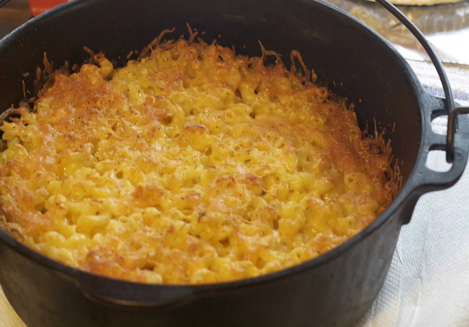 Baked macaroni and cheese with a golden, crusty top in a cast-iron Dutch oven