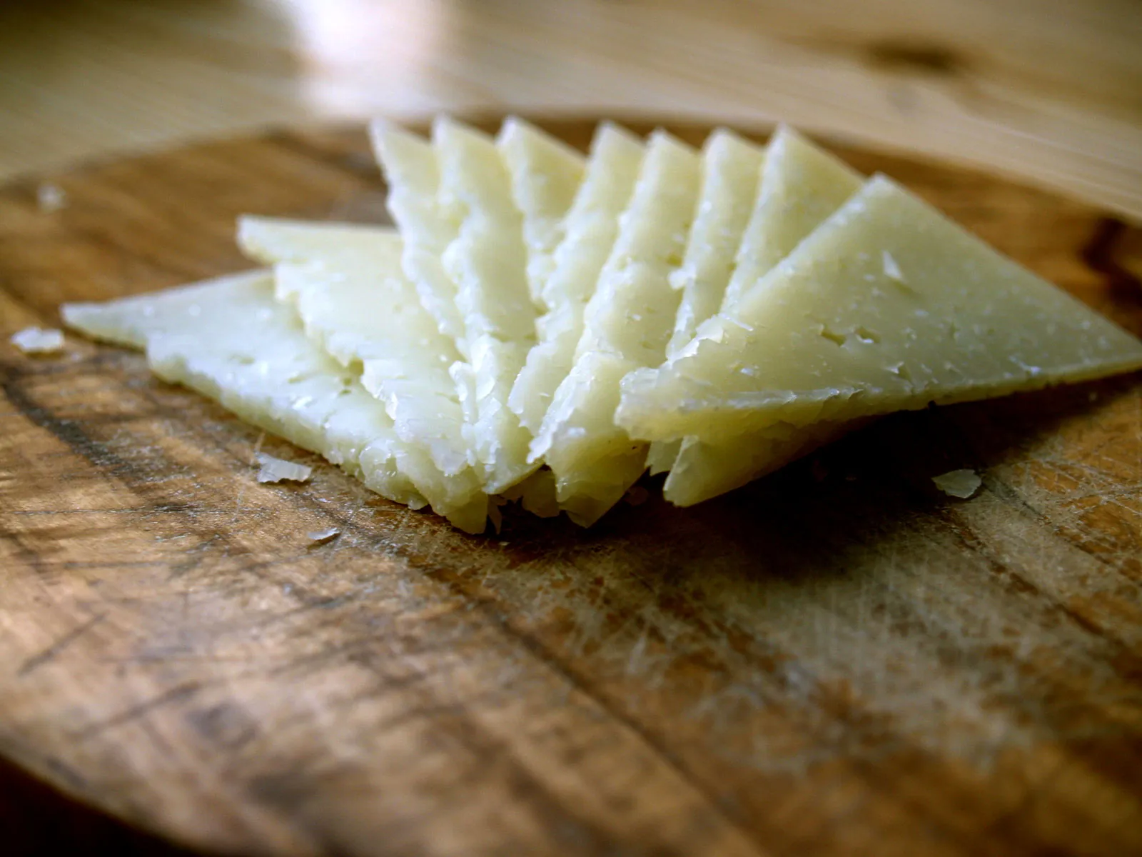 Thin triangles of Manchego fanned out on a wooden board