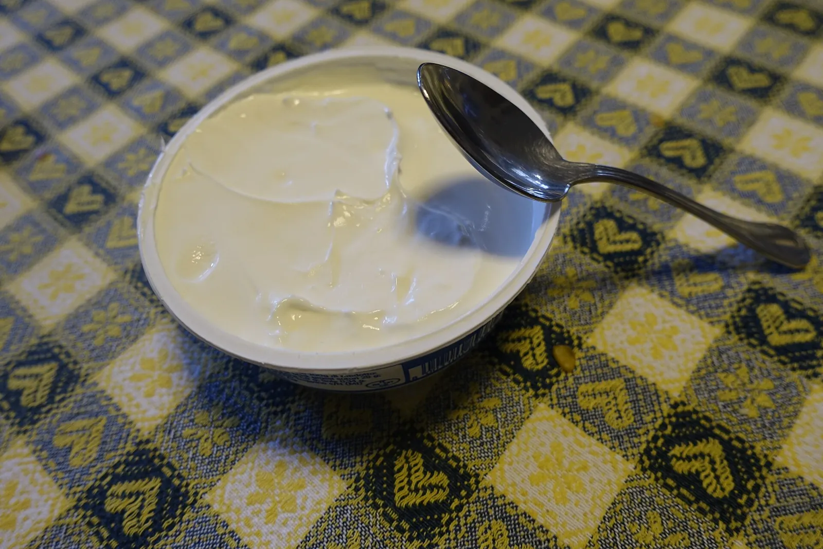 An open tub of thick white mascarpone with a spoon resting in it