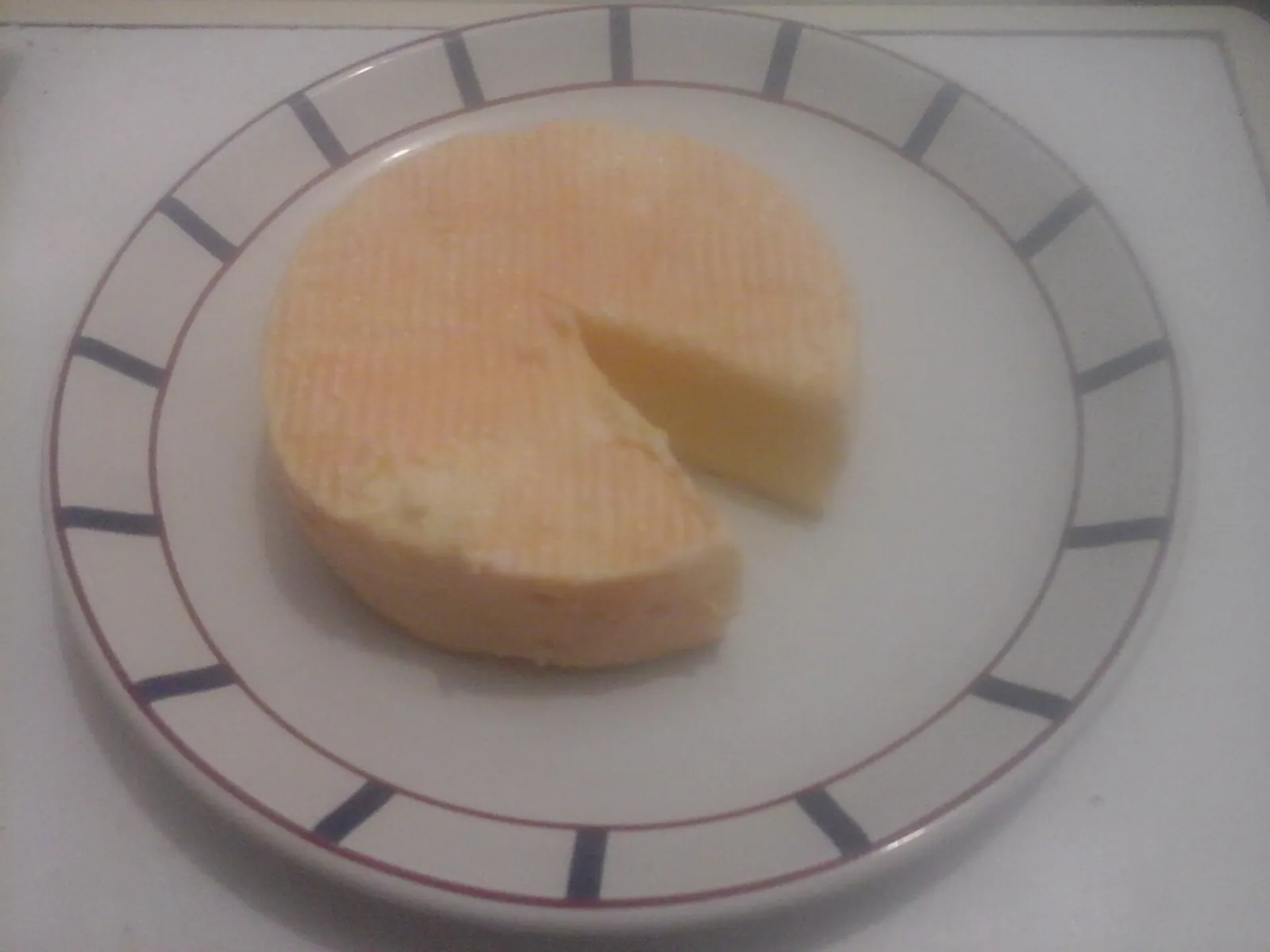 A small round of French Munster-Géromé with an orange rind and a wedge cut out