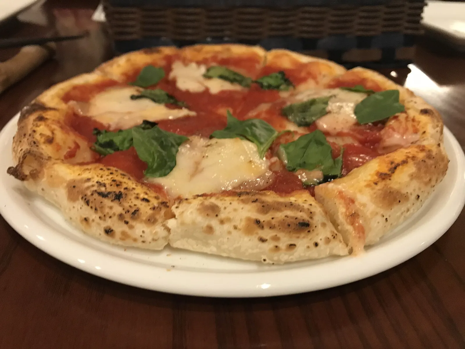 A Neapolitan-style margherita pizza with melted mozzarella, tomato and basil