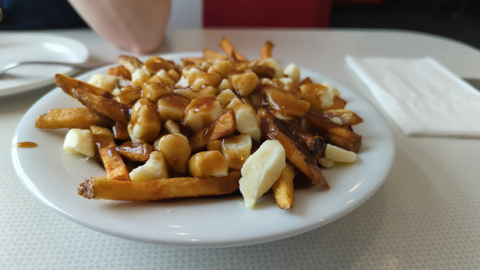 A plate of poutine: fries covered in gravy and white cheese curds