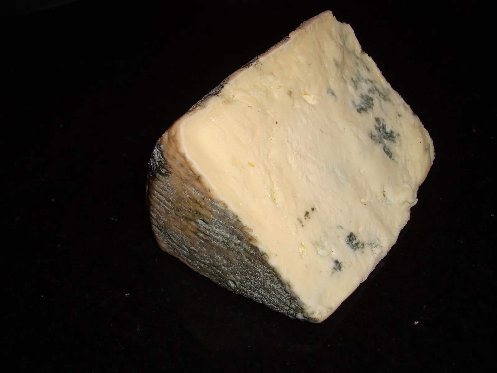 A wedge of Cashel Blue with a natural grey rind and a creamy ivory paste marked by scattered blue green veins