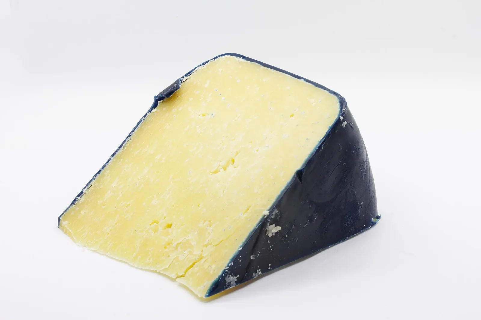 A wedge of cheddar with a pale yellow, firm paste and a dark wax coating along one side, photographed on white