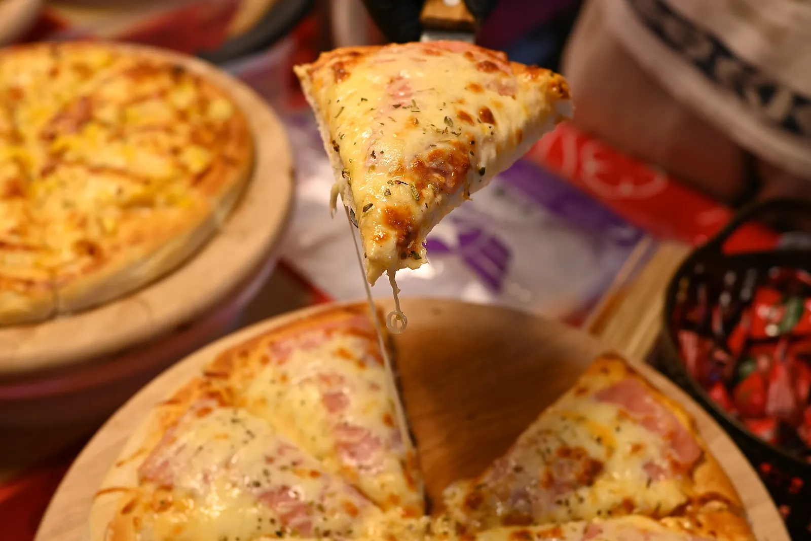 Golden baked cheese pizza with a lifted slice pulling long melted cheese strings over the rest of the pie.