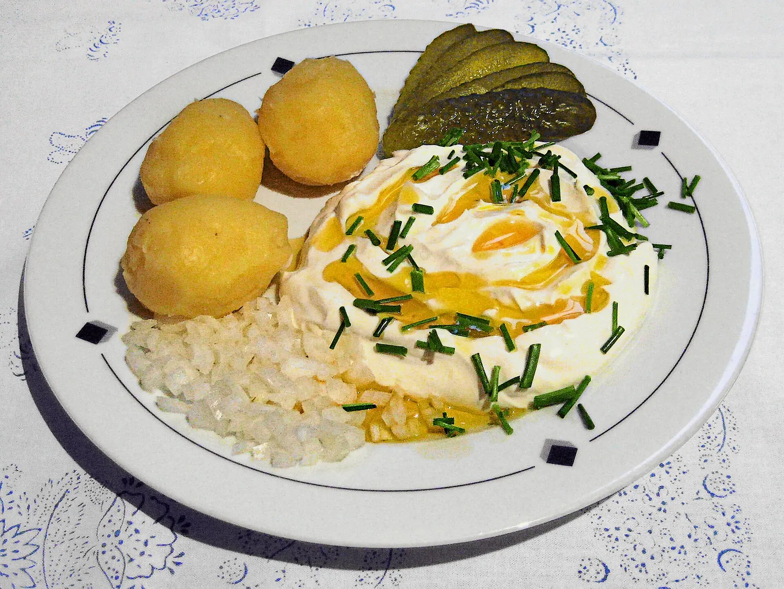Quark with linseed oil, chives and onions beside boiled potatoes and a pickle