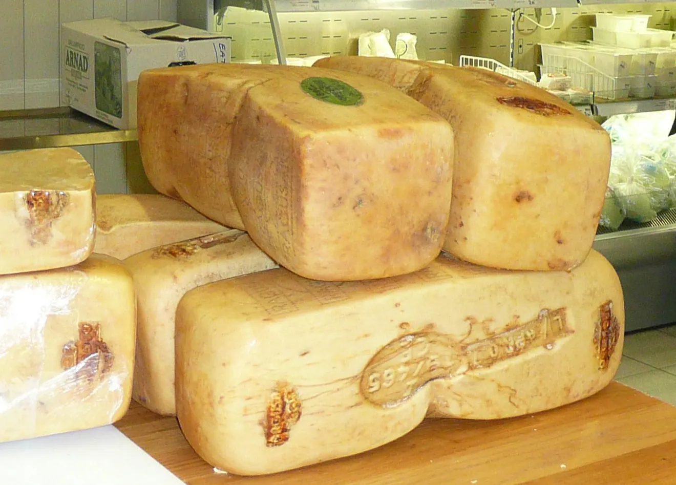 Several rectangular blocks of Ragusano, a Sicilian cheese with a stamped rind and rope marks, stacked on a counter in a shop.
