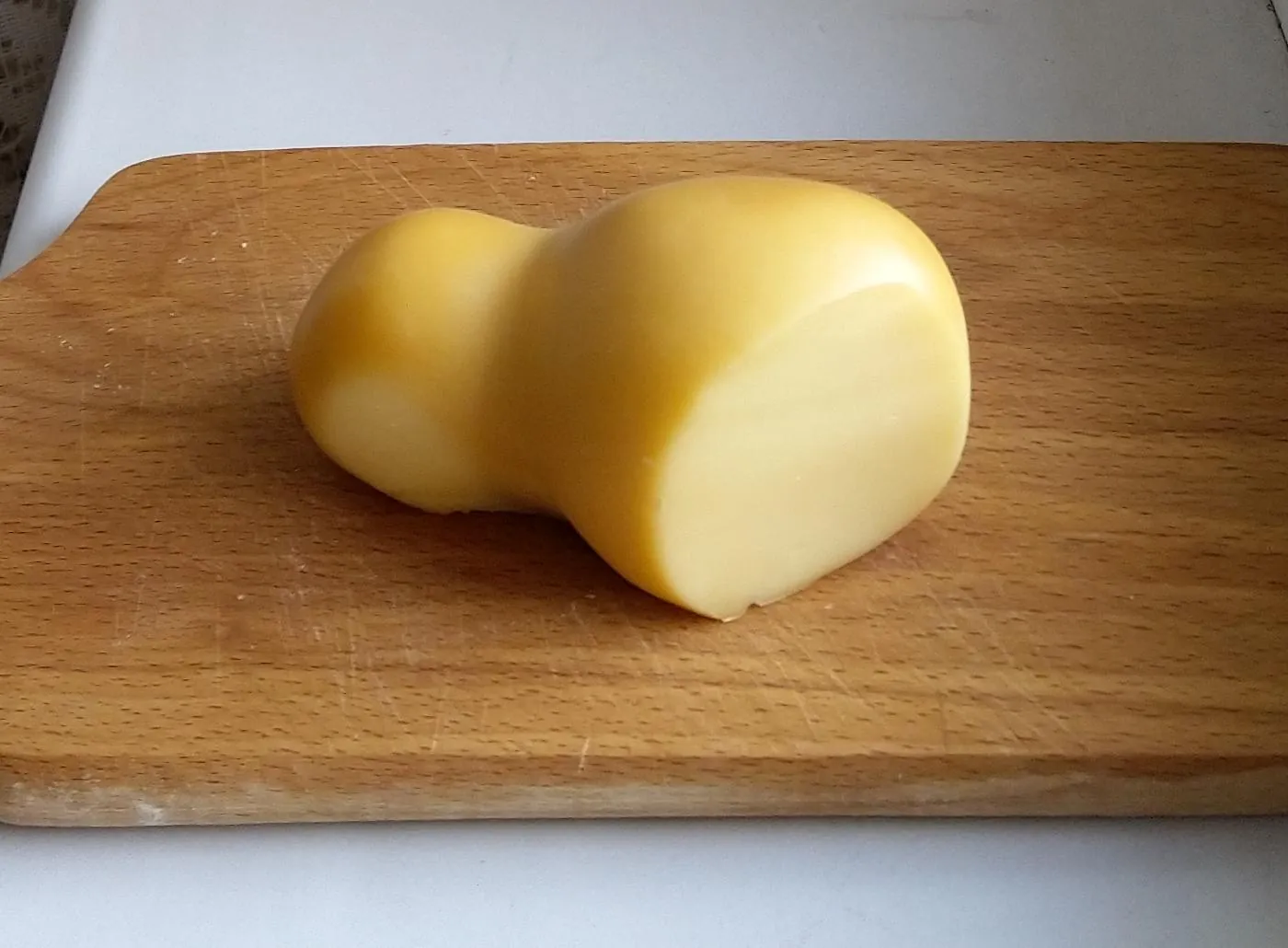 A pear-shaped smoked scamorza on a wooden board