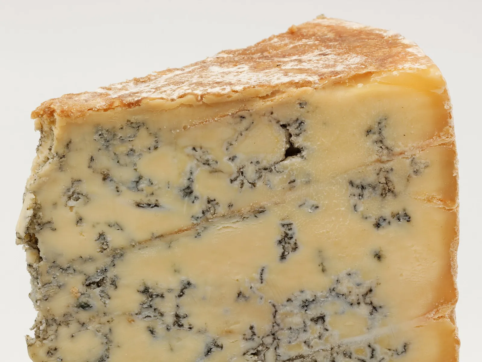 A wedge of Blue Stilton with its crusty rind and blue veins