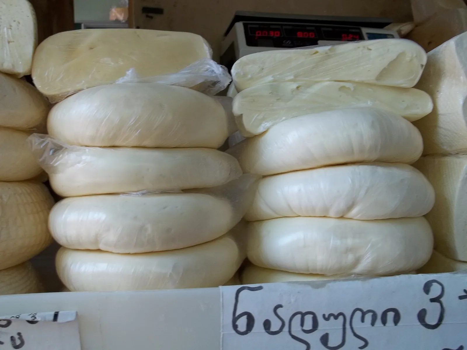 Stacks of white sulguni cheese discs at a market stall