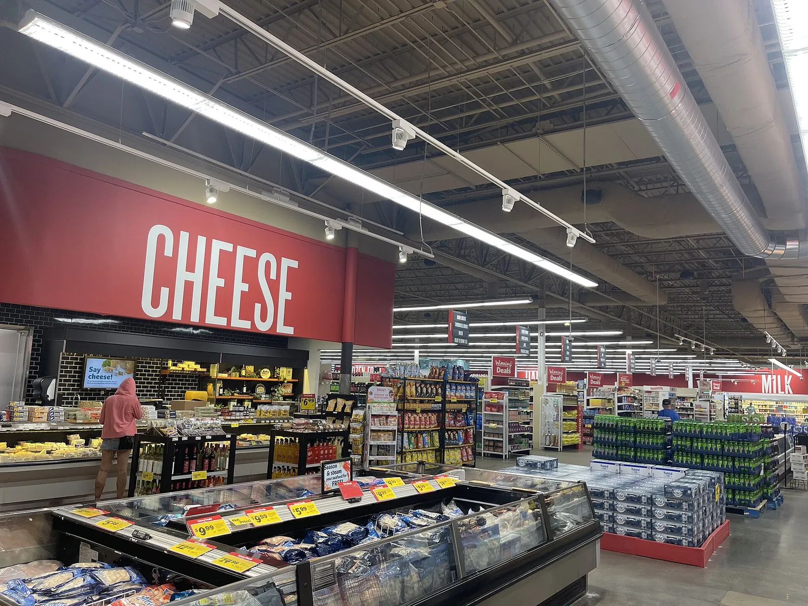 The cheese section of a large supermarket under a big CHEESE sign