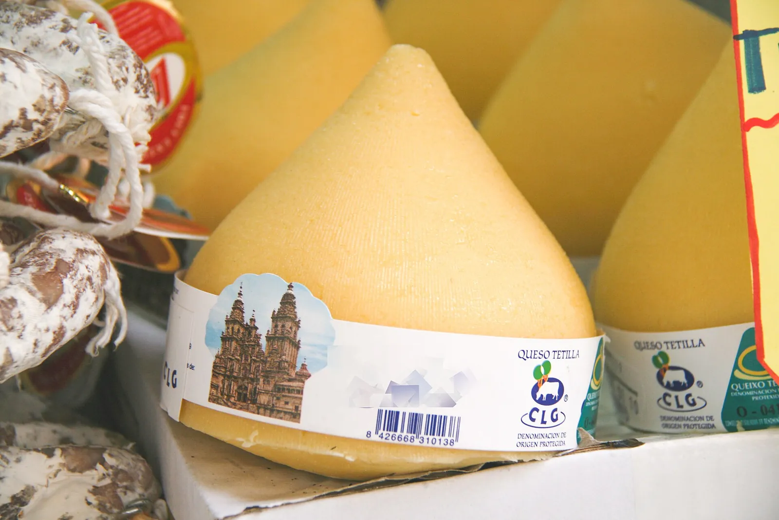 Pear shaped Tetilla cheeses with paper bands lined up in a shop display