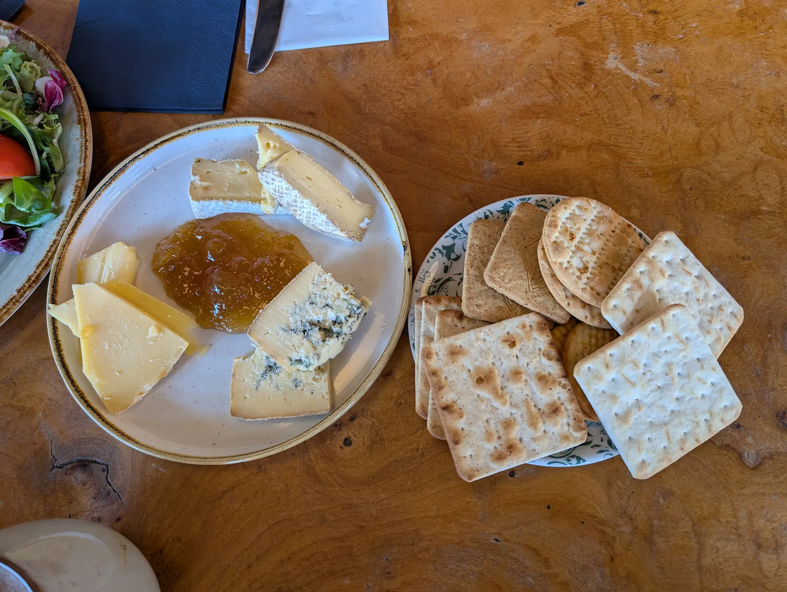 Three cheeses, one of them blue, with jam and crackers on two plates