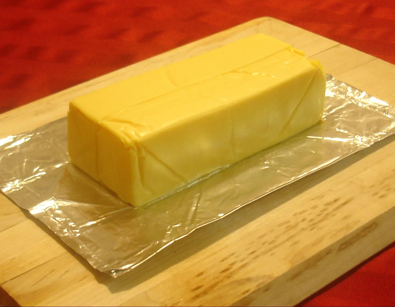 An unwrapped loaf of Velveeta on its foil wrapper on a cutting board