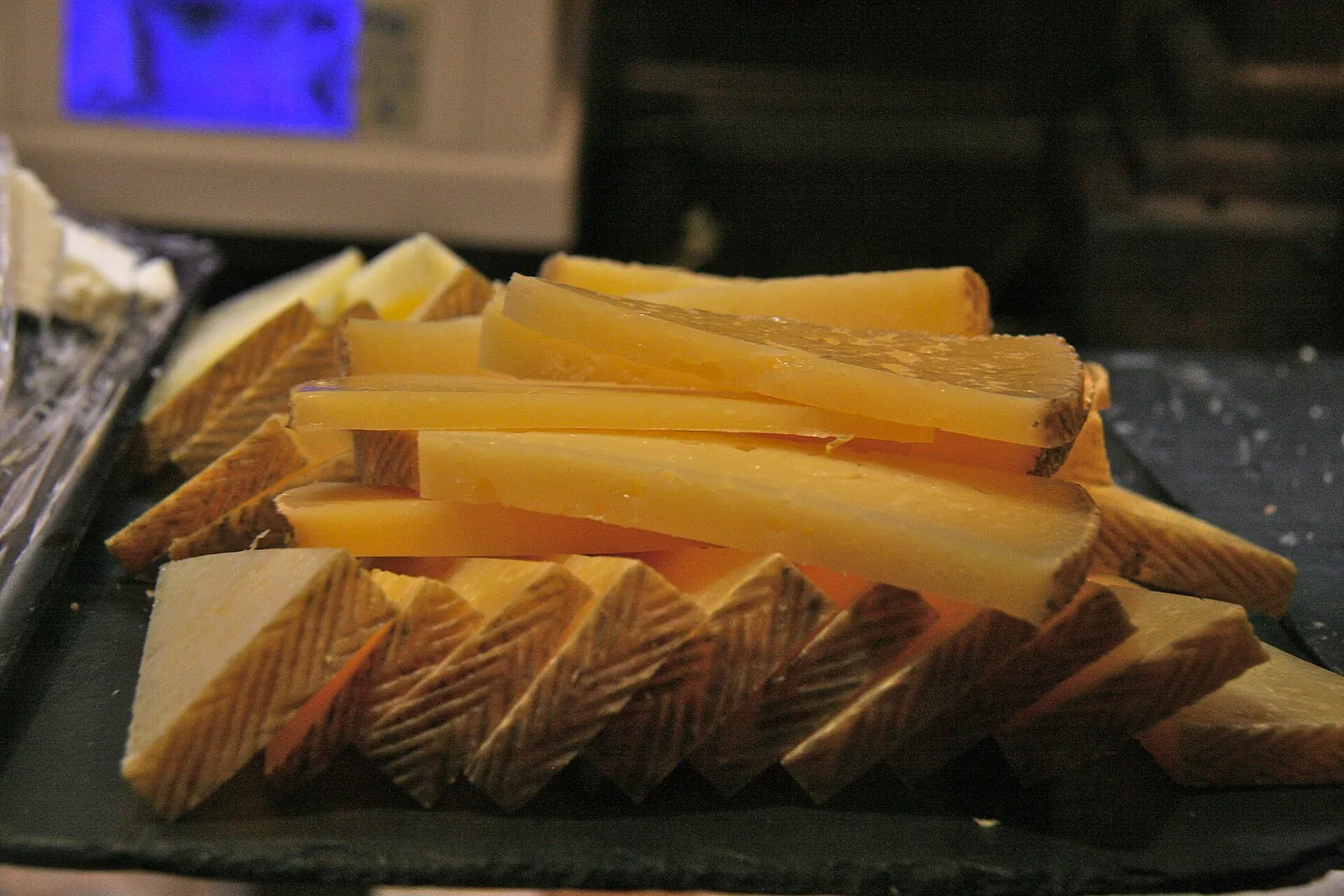 Thin slices of Zamorano cheese fanned over a slate board with the zigzag pressed rind visible